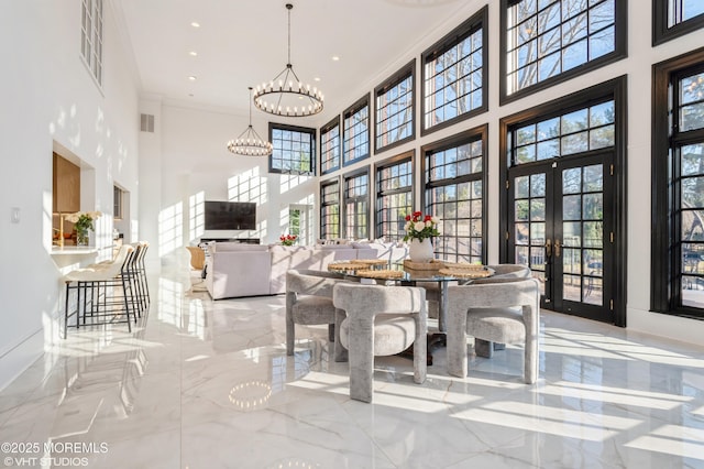 dining room with french doors, ornamental molding, a chandelier, and a high ceiling