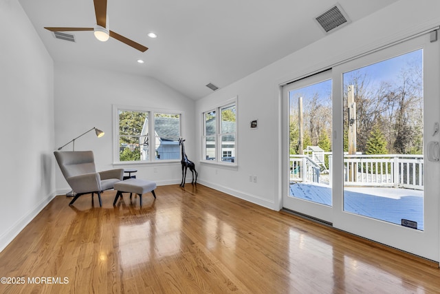 sitting room with ceiling fan, light wood-type flooring, and vaulted ceiling