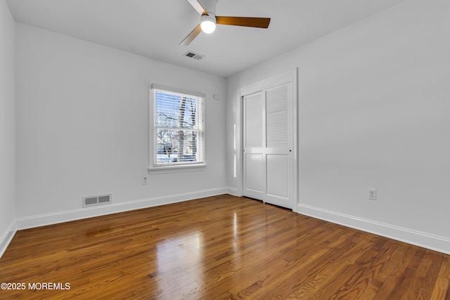 unfurnished bedroom featuring ceiling fan, a closet, and wood-type flooring