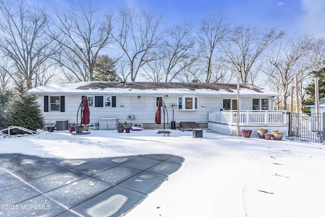 snow covered back of property featuring central AC and a wooden deck