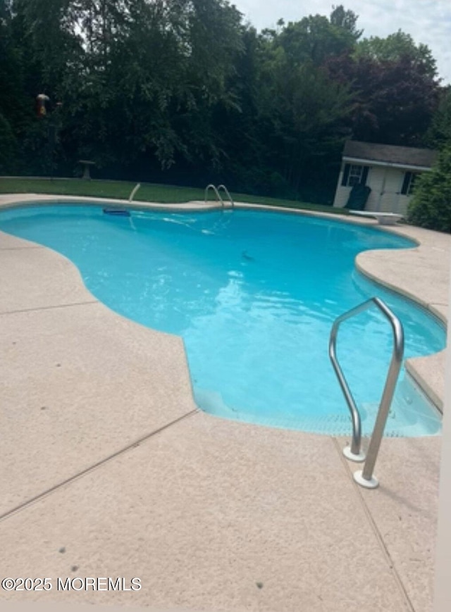 view of swimming pool featuring an outbuilding