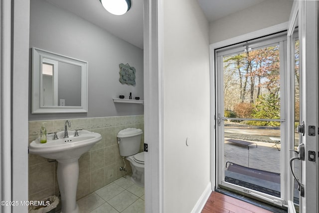 bathroom with tile patterned flooring, toilet, and tile walls