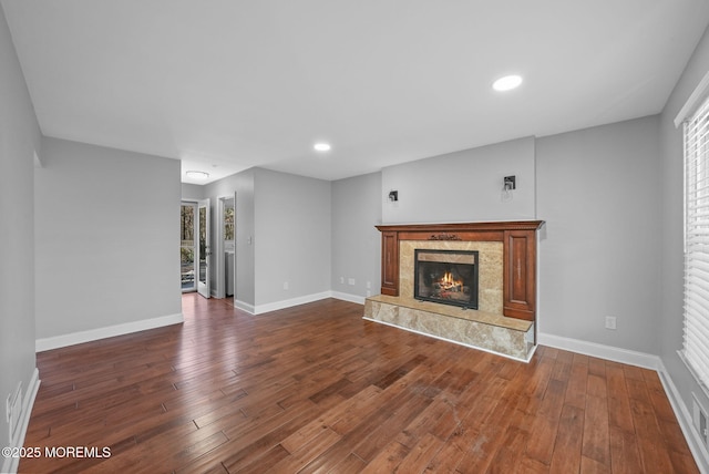 unfurnished living room featuring a high end fireplace and dark wood-type flooring