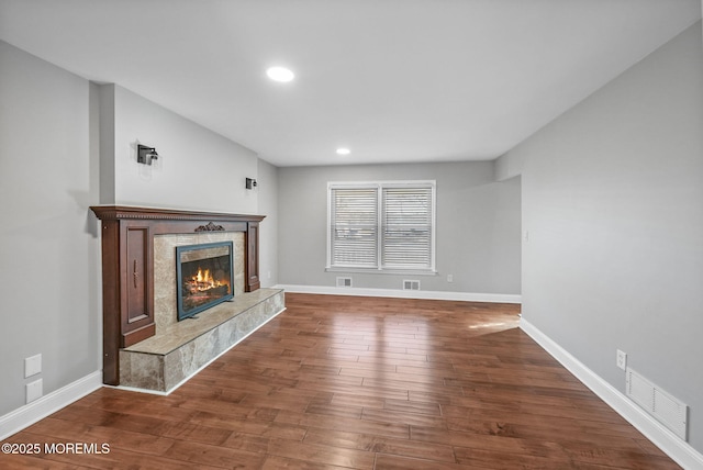 unfurnished living room featuring a tile fireplace and hardwood / wood-style floors