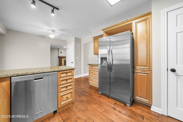 kitchen with ceiling fan, dark hardwood / wood-style floors, light stone countertops, and stainless steel appliances