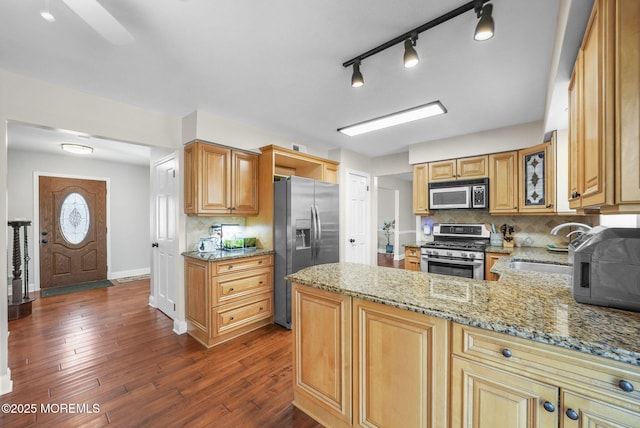 kitchen featuring light stone countertops, dark hardwood / wood-style flooring, kitchen peninsula, decorative backsplash, and appliances with stainless steel finishes