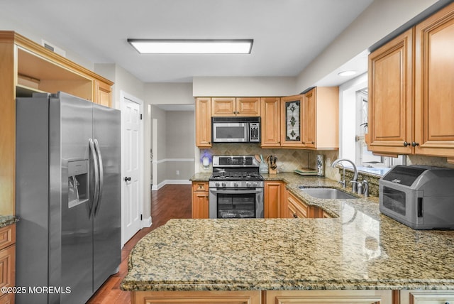 kitchen featuring hardwood / wood-style floors, sink, light stone countertops, kitchen peninsula, and stainless steel appliances