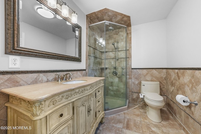 bathroom with vanity, toilet, a shower with door, and tile walls