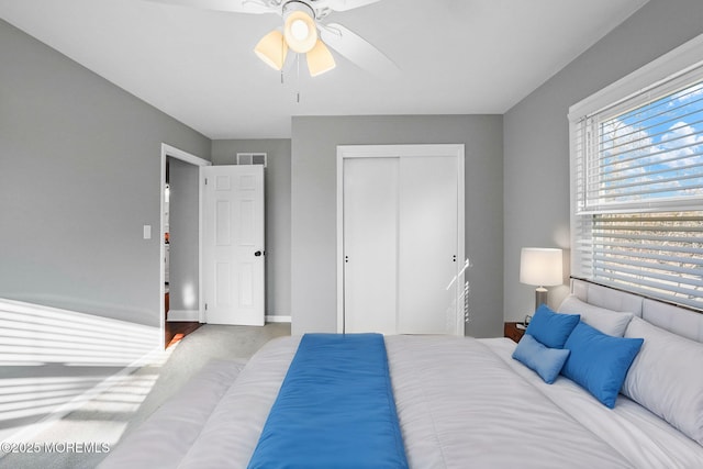 carpeted bedroom with ceiling fan and a closet