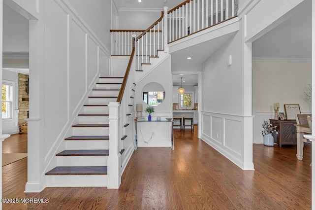 staircase with hardwood / wood-style flooring, ornamental molding, and a high ceiling