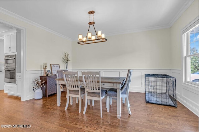 dining area featuring hardwood / wood-style floors, ornamental molding, and a notable chandelier