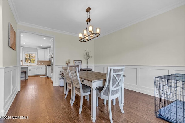 dining room with hardwood / wood-style floors, a notable chandelier, ornamental molding, and sink