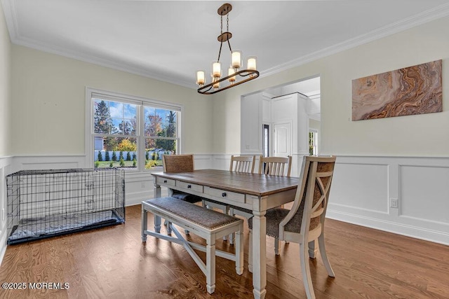 dining area featuring hardwood / wood-style flooring, a notable chandelier, and crown molding