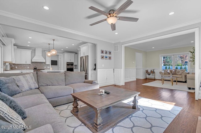 living room with light hardwood / wood-style flooring, ceiling fan, and crown molding