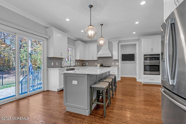 kitchen featuring white cabinetry, a kitchen island, stainless steel appliances, and custom range hood