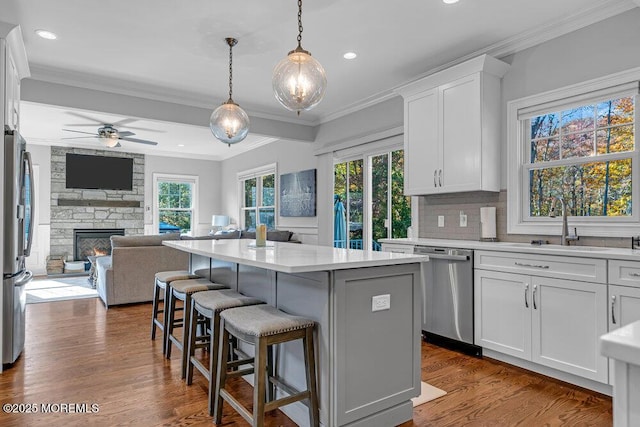 kitchen featuring a fireplace, appliances with stainless steel finishes, a center island, and white cabinetry