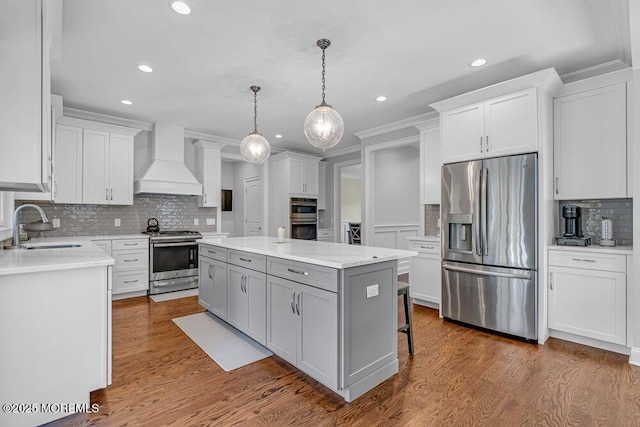 kitchen featuring premium range hood, white cabinets, sink, a kitchen island, and stainless steel appliances