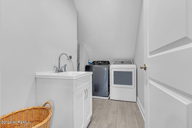 laundry area with cabinets, separate washer and dryer, and sink