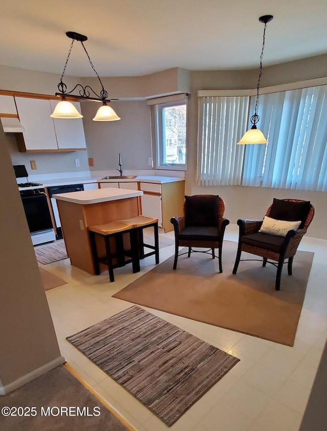 interior space with a center island, white stove, sink, hanging light fixtures, and a kitchen bar