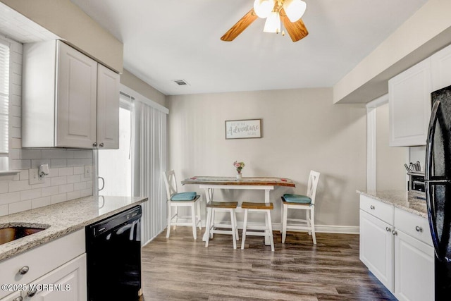 kitchen with black appliances, light stone countertops, and white cabinetry