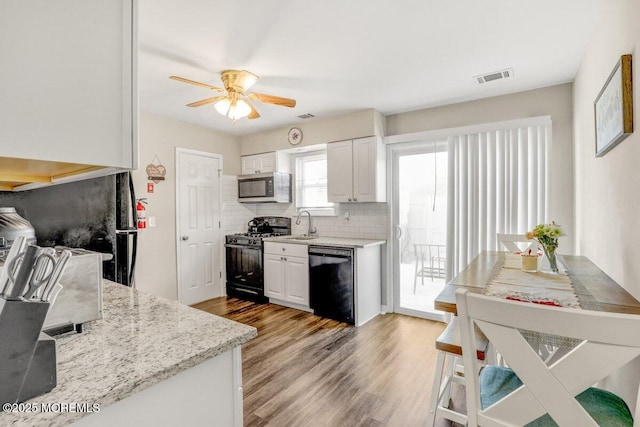 kitchen featuring ceiling fan, tasteful backsplash, light hardwood / wood-style floors, white cabinets, and black appliances