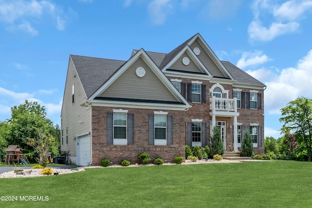 view of front of property featuring a front yard, a balcony, and a garage