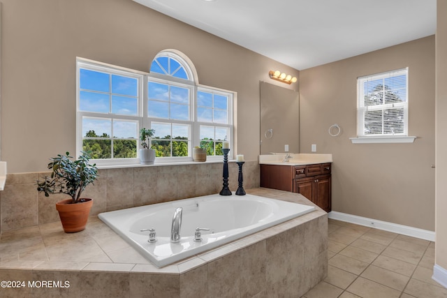 bathroom with tile patterned floors, vanity, a relaxing tiled tub, and plenty of natural light