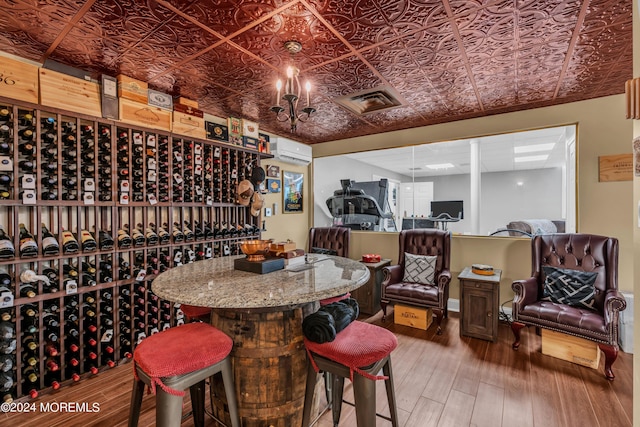 wine cellar featuring a wall mounted AC, a notable chandelier, and hardwood / wood-style flooring