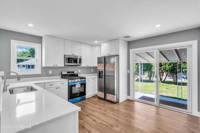 kitchen featuring a wealth of natural light, stainless steel appliances, white cabinetry, and sink