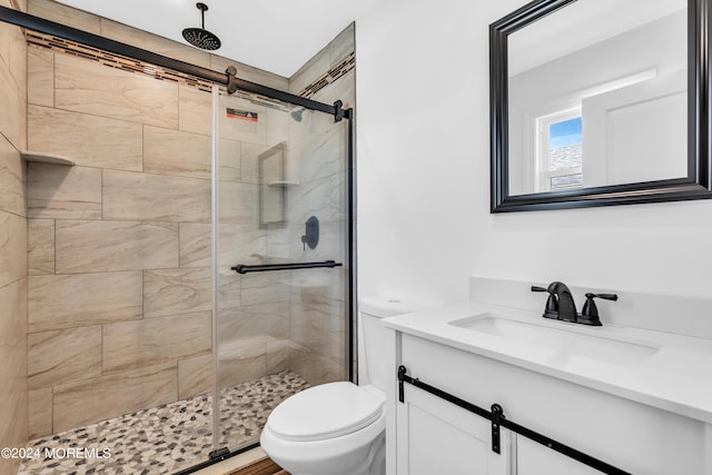 bathroom with toilet, vanity, and a shower with door