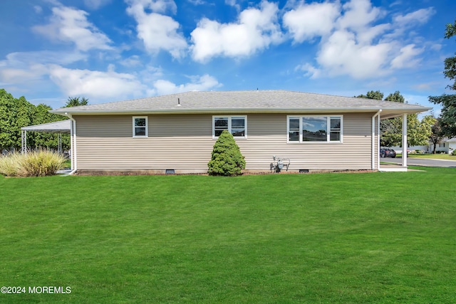 rear view of house featuring a carport and a yard