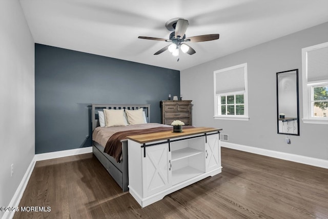 bedroom with multiple windows, dark wood-type flooring, and ceiling fan