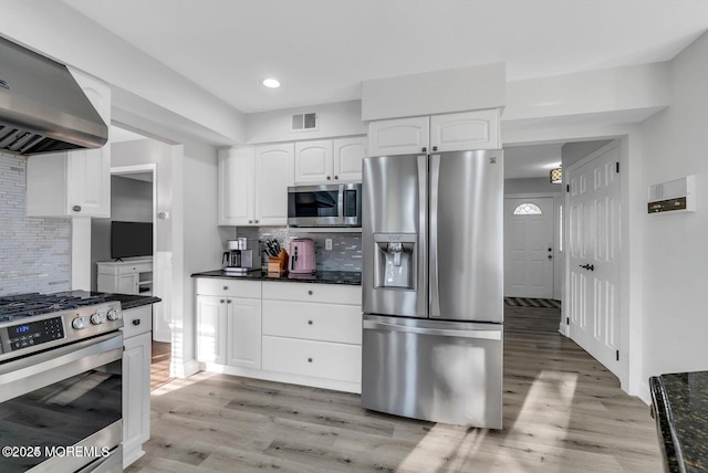 kitchen featuring tasteful backsplash, appliances with stainless steel finishes, white cabinets, and wall chimney exhaust hood