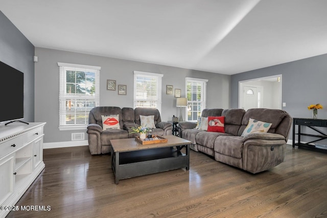 living room with dark hardwood / wood-style floors and a healthy amount of sunlight