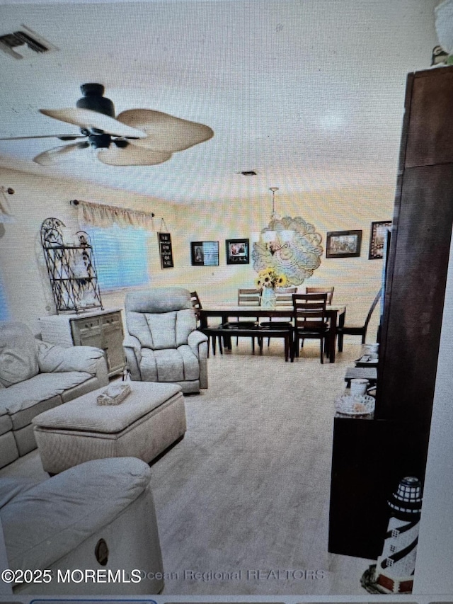 living room with ceiling fan with notable chandelier