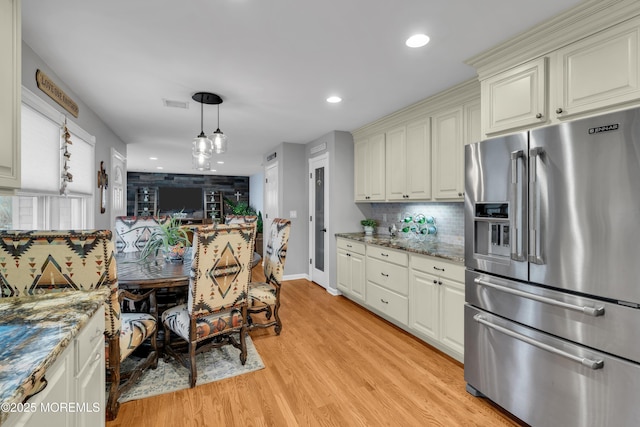 kitchen with dark stone countertops, light wood-type flooring, pendant lighting, decorative backsplash, and high end refrigerator