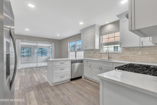 kitchen featuring white cabinets, sink, kitchen peninsula, and stainless steel appliances