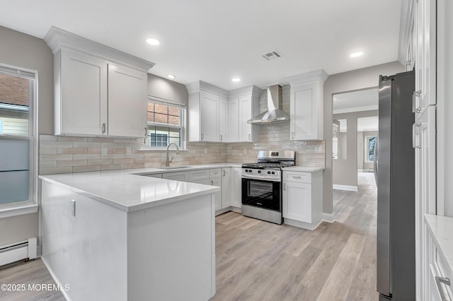 kitchen featuring appliances with stainless steel finishes, white cabinetry, wall chimney exhaust hood, and sink