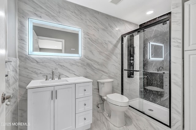 bathroom with vanity, toilet, a shower with door, and tile walls