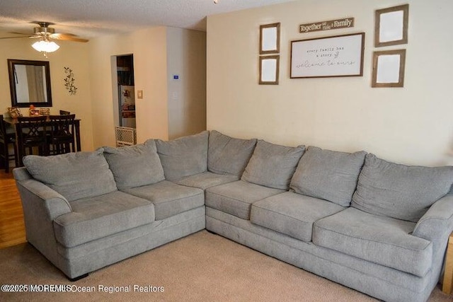 carpeted living room featuring a textured ceiling and ceiling fan