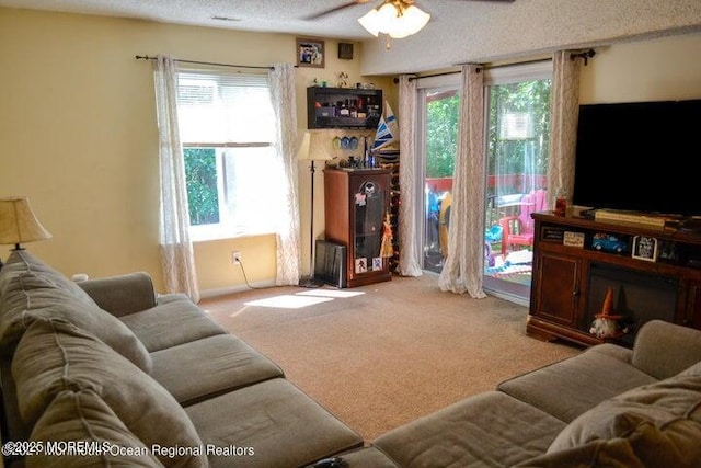 carpeted living room featuring ceiling fan and a textured ceiling