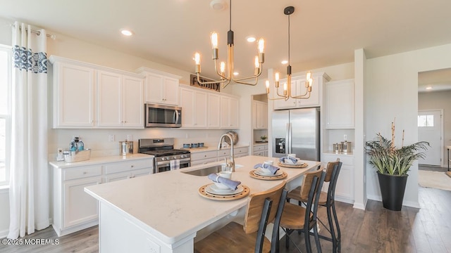 kitchen with appliances with stainless steel finishes, white cabinetry, and a kitchen island with sink