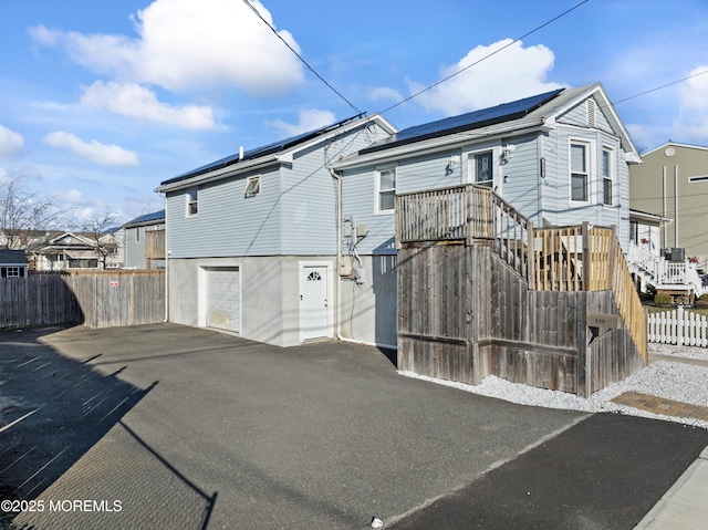 rear view of house featuring solar panels and a garage