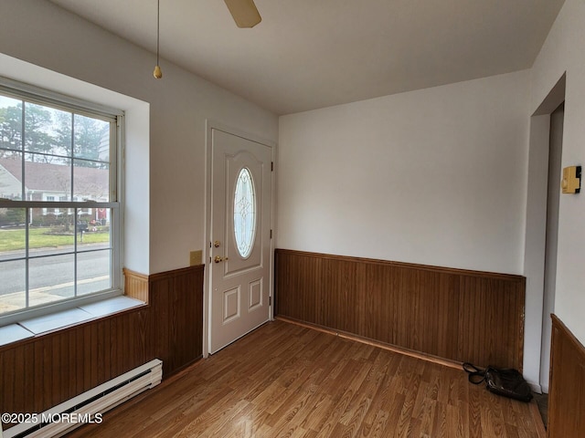 entryway featuring wood-type flooring, baseboard heating, and wooden walls