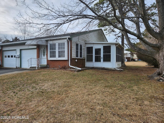 view of front of property with a sunroom, a front lawn, and a garage