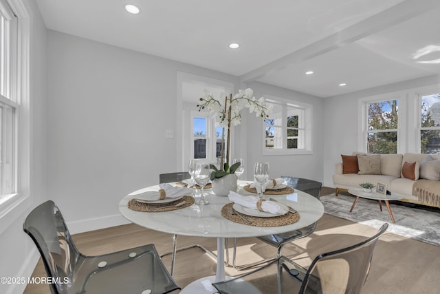 dining area with beam ceiling and light wood-type flooring