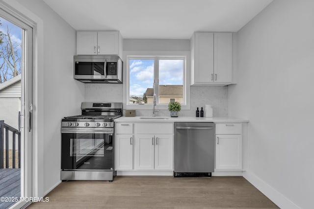 kitchen featuring backsplash, sink, white cabinets, and stainless steel appliances