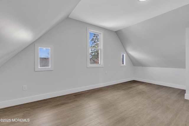 additional living space featuring lofted ceiling and light wood-type flooring