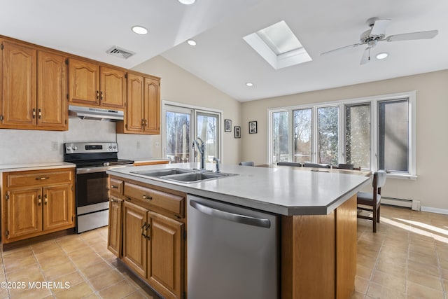 kitchen with a kitchen island with sink, appliances with stainless steel finishes, ceiling fan, lofted ceiling with skylight, and sink