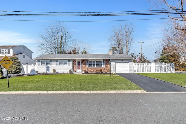 ranch-style home with brick siding, a chimney, a front yard, a garage, and driveway